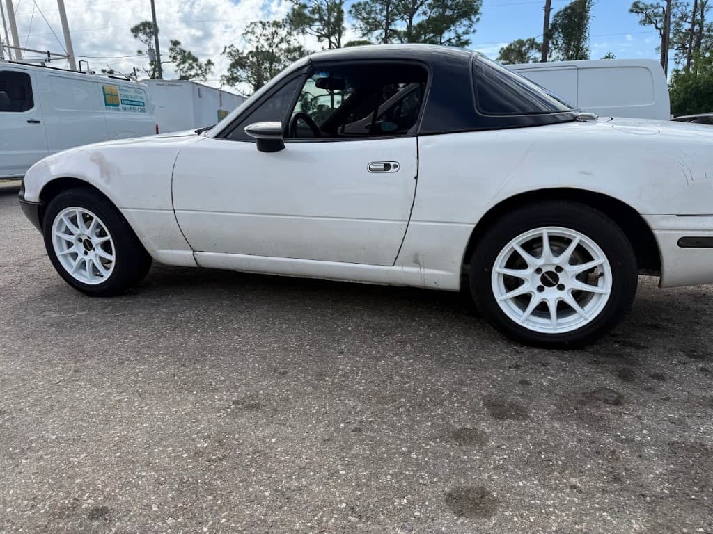 White Mazda Miata with aftermarket white wheels and performance tires